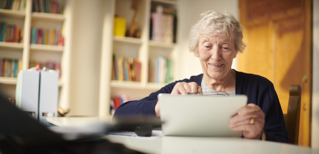 senior woman waving to her family on her digital tablet