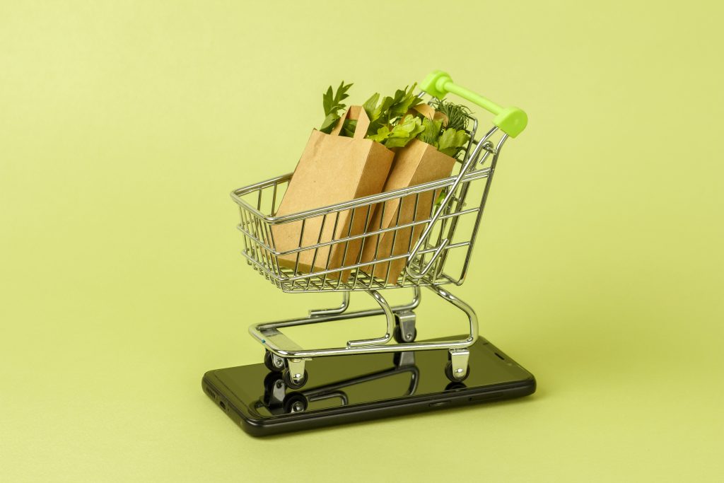 Paper shopping bags with fresh green salad in cart, trolley. Urban eco foods delivery mobile online application concept. Service app.